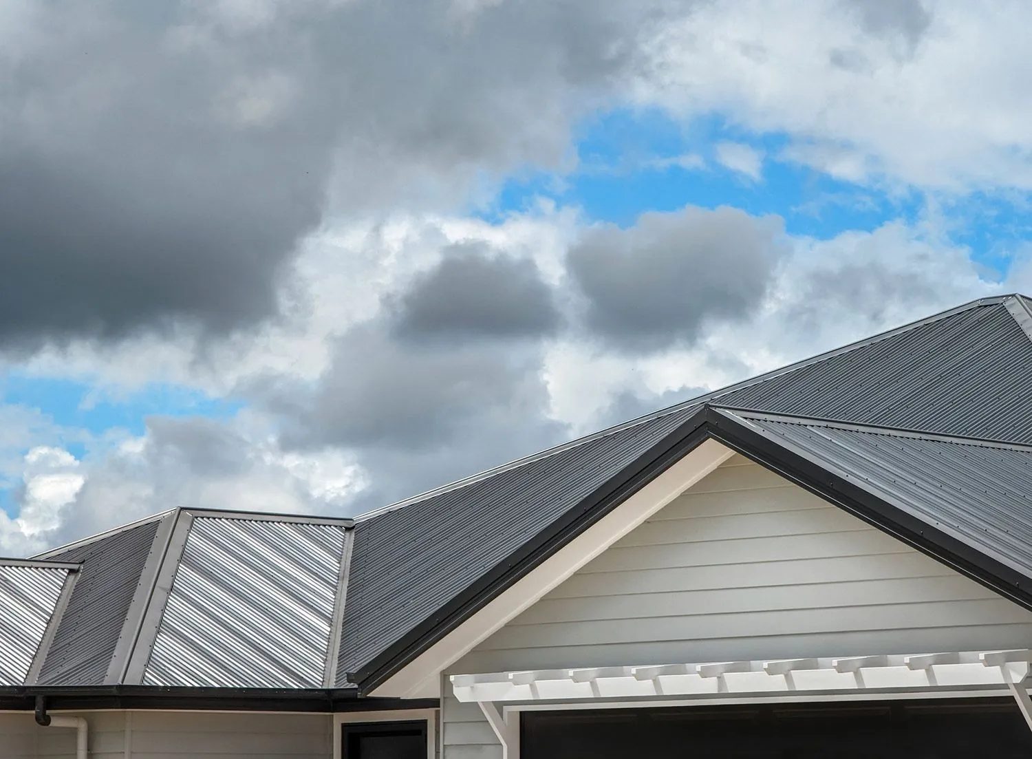 Gray metal roof with dark trim on a home with pale siding