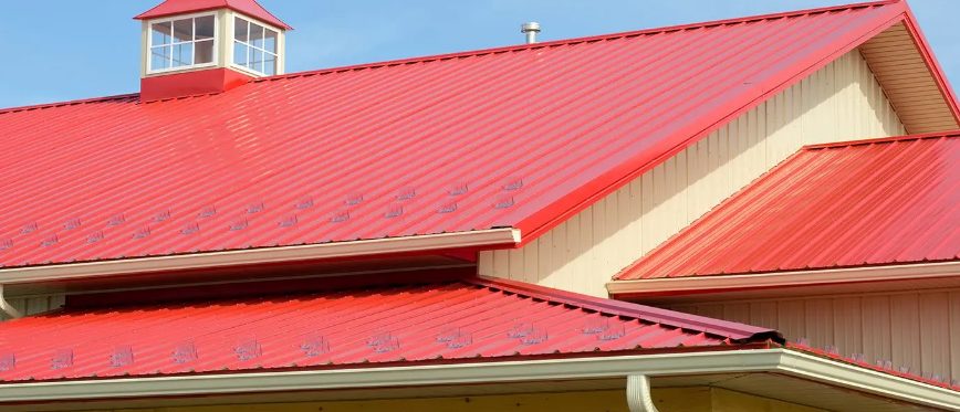 Red metal roof on a barn with a cupola